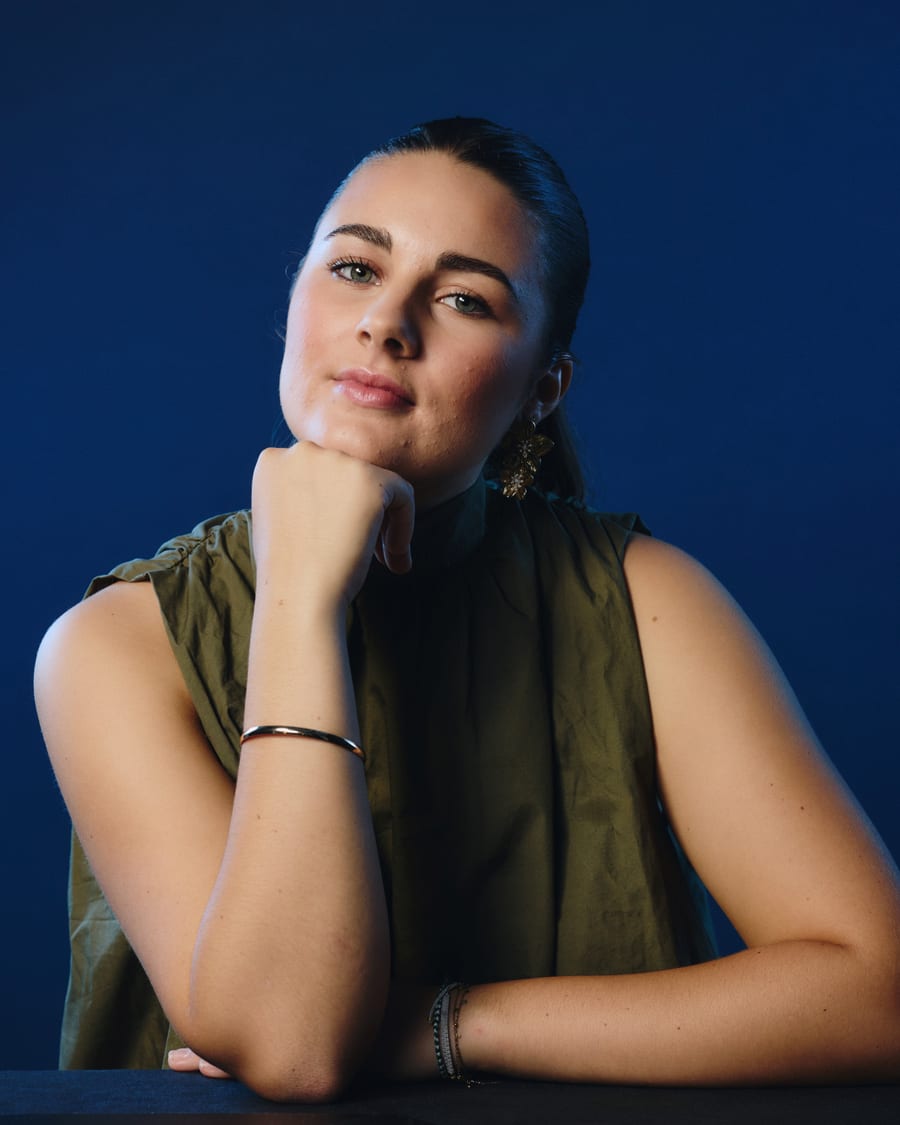 Portrait de Romane, accoudée, sur fond bleu